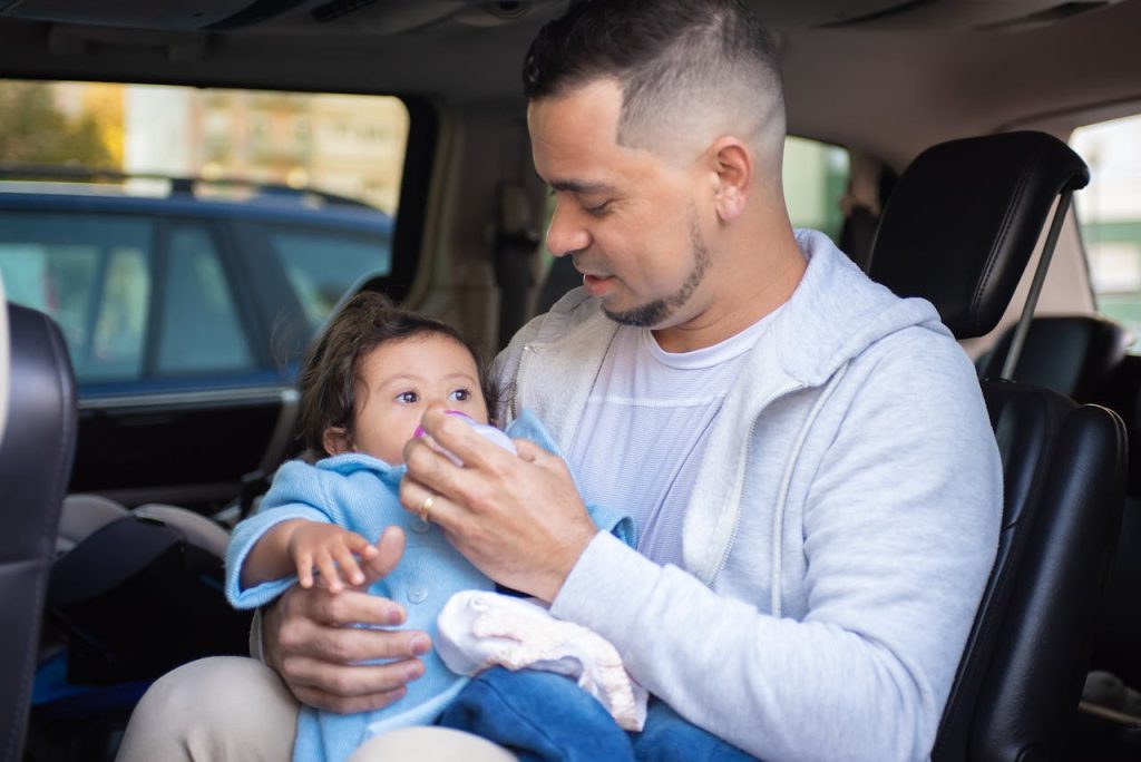 A Man Feeding His Child with a Bottle of Milk